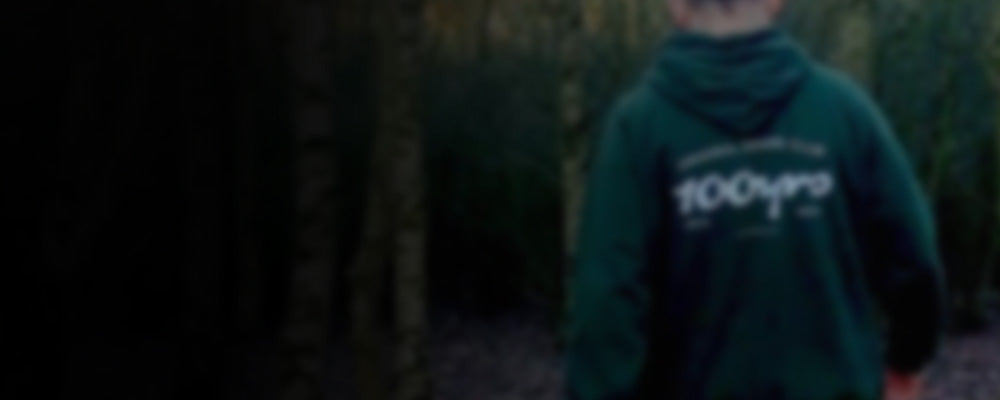 A man wearing a green hoodie while walking through the woods