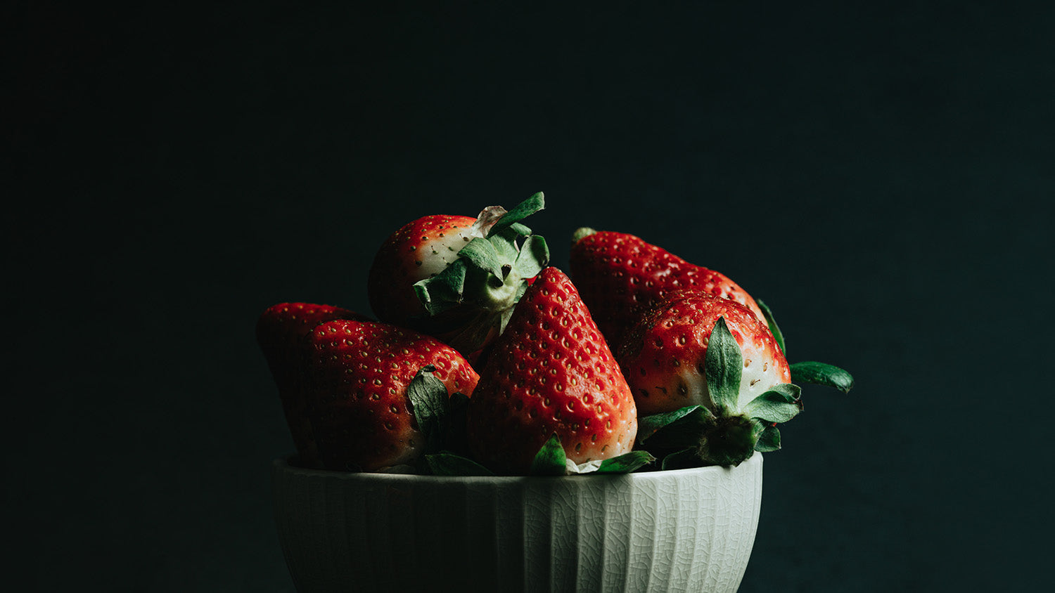 Delicious red strawberries in a white bowl.