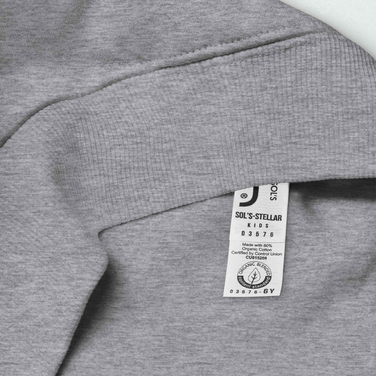 Close-up of the tag on the Unisex Kids Eco Hoodie showing organic cotton and recycled polyester blend from the 100yrs Logo collection.