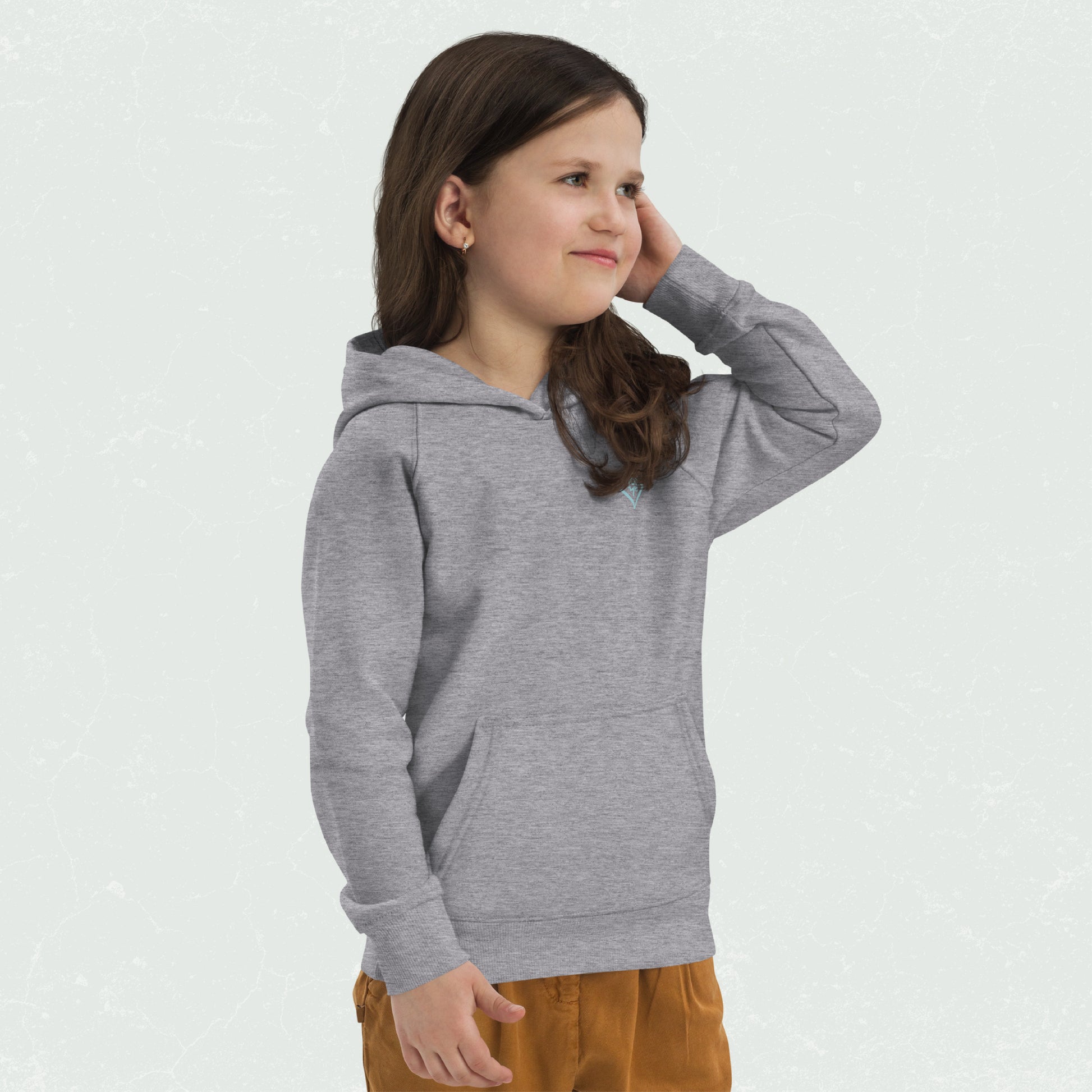 Kid wearing a grey unisex eco hoodie with 100yrs logo, front pouch pocket, and ribbed cuffs and hem for warmth, stands smiling with left hand behind head.