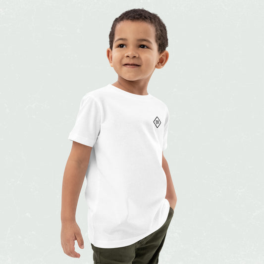 Child wearing a white unisex organic kids t-shirt with 100yrs logo, looking to the side with hands in pockets.