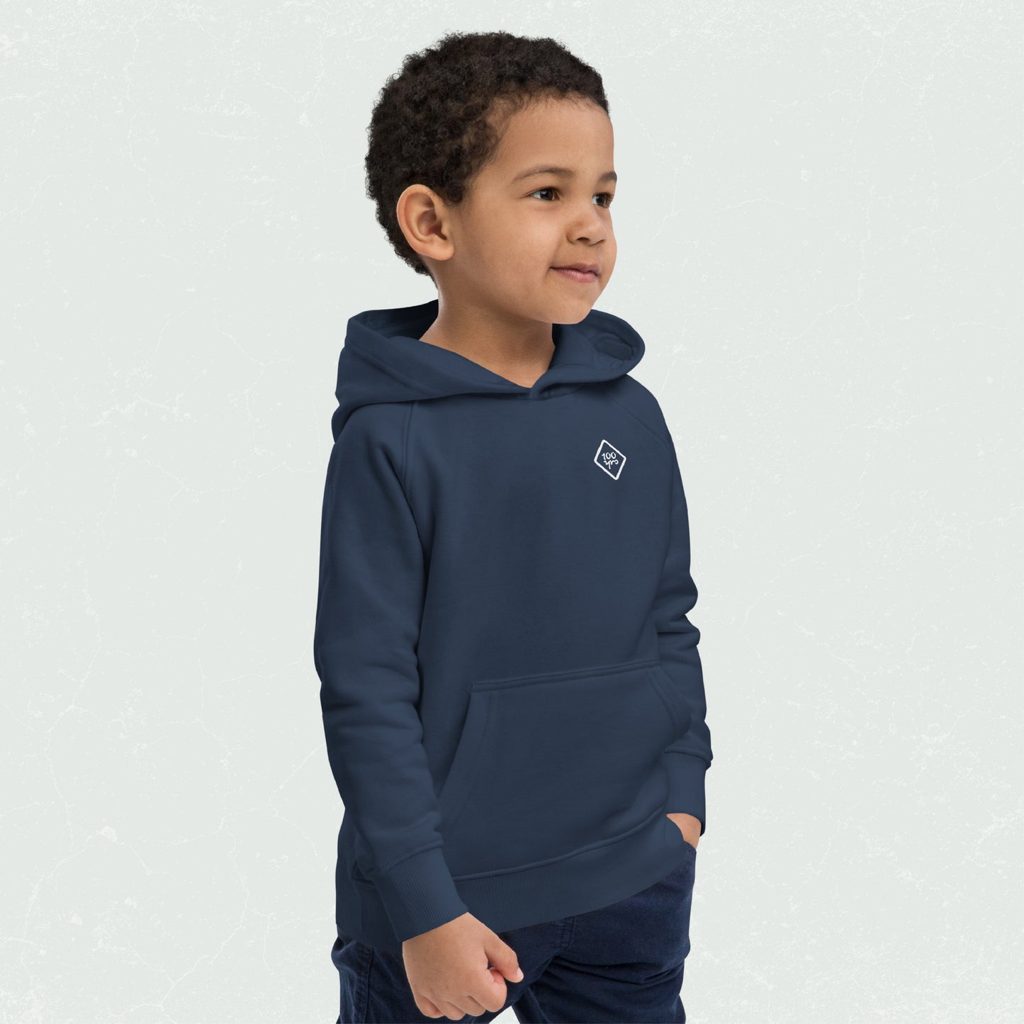 Kid wearing a blue eco-friendly Unisex Kids Eco Hoodie with 100yrs logo, hands in front pocket, looking to the side, casual and comfy.