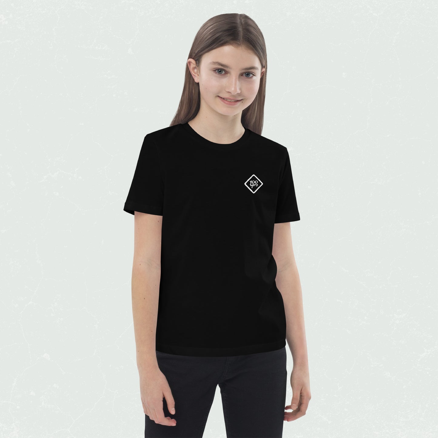 Unisex Organic Kids T-Shirt with 100yrs Logo in black, featuring a comfy relaxed fit and set-in sleeves, modeled by a smiling child.