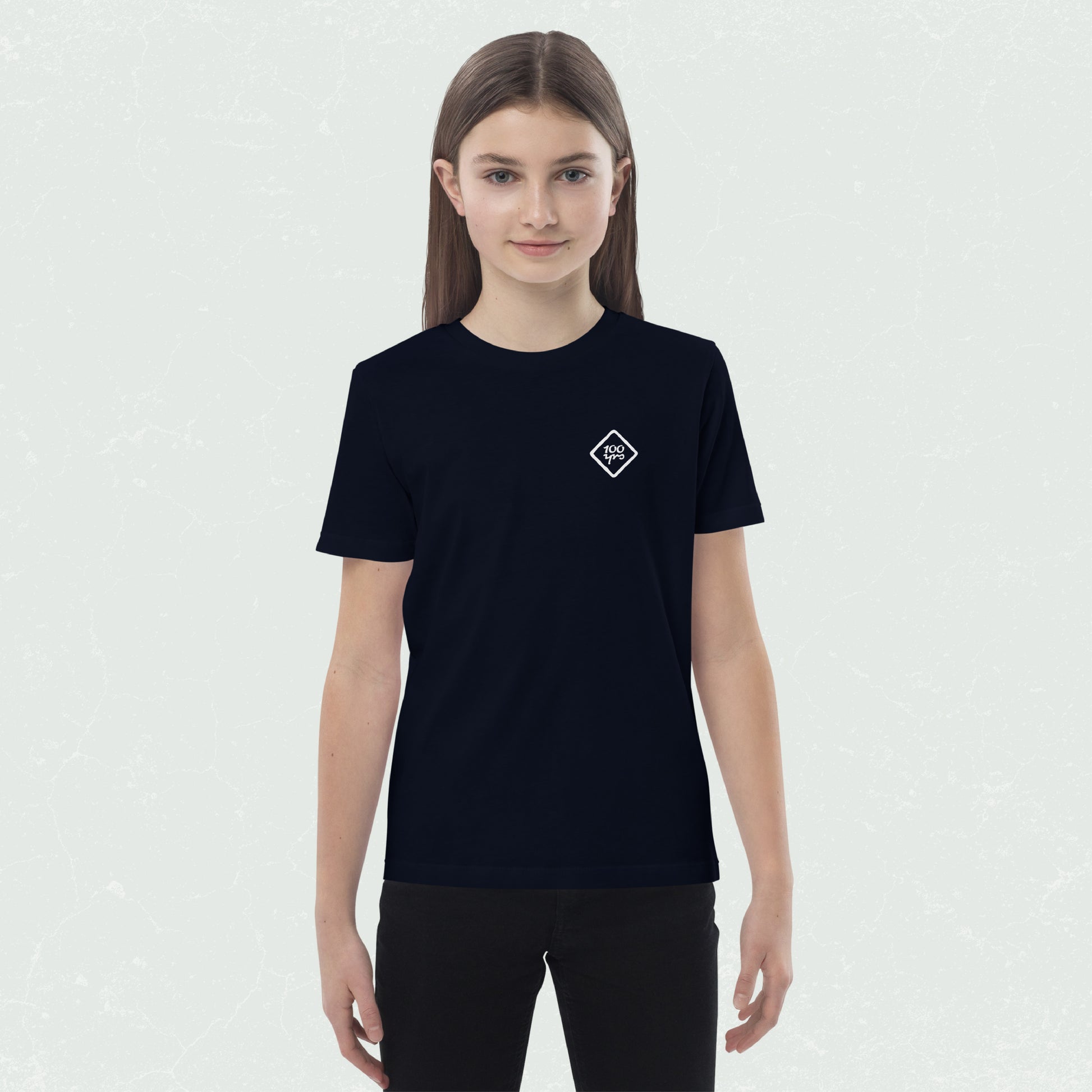 Kid wearing a black unisex organic t-shirt with a small "100yrs" logo on the chest.